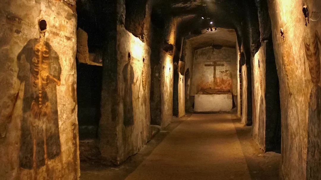 Catacombs of San Gaudioso corridor with ancient frescoes and burial niches.