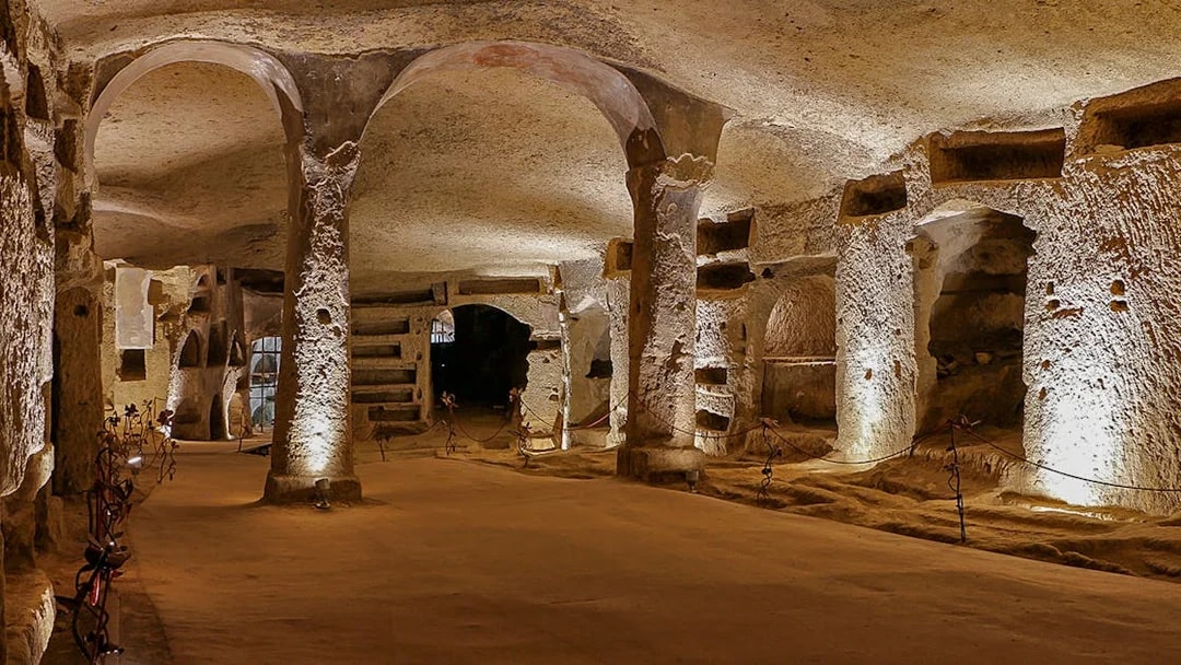 Exploring the ancient Catacombs of San Gennaro in Naples, Italy, with illuminated arches and tombs.