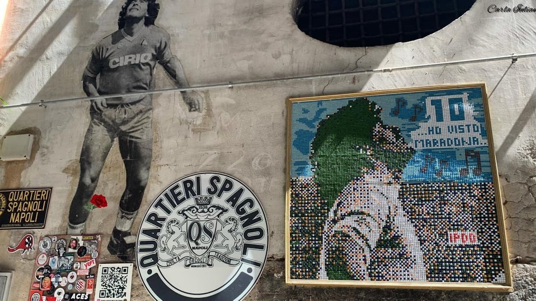 Mural of Diego Maradona in Quartieri Spagnoli, Naples, with mosaic art and local street signs.