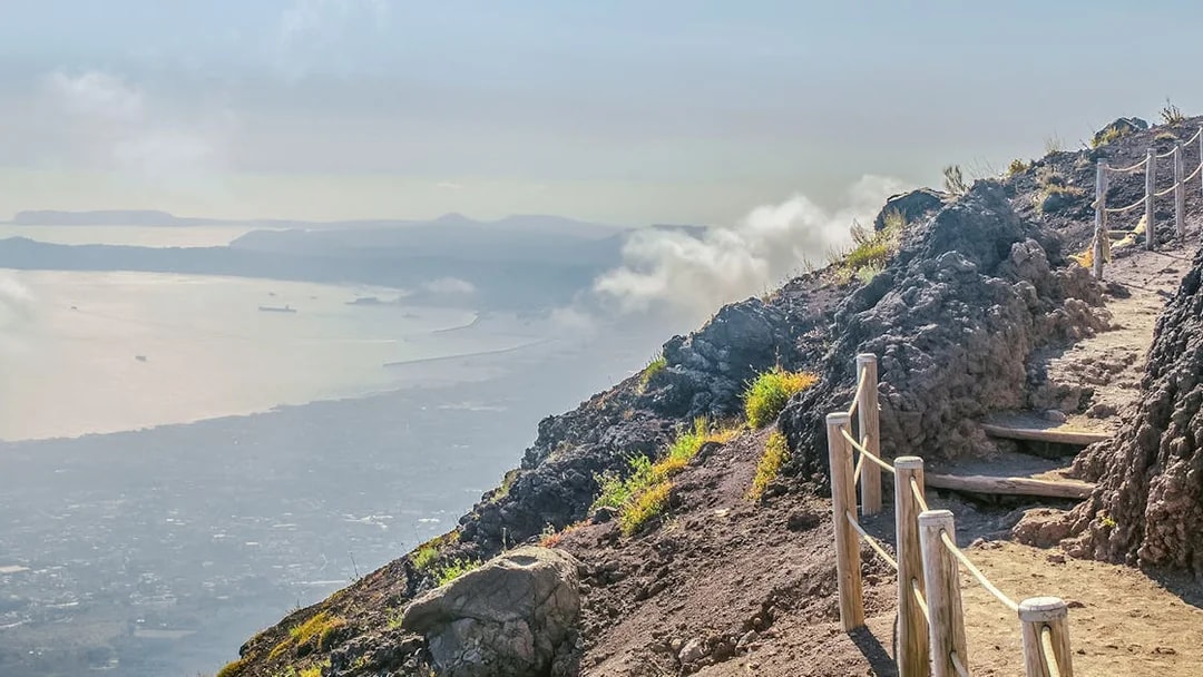 Pathway along Mount Vesuvius with view of Naples coastline in the distance.