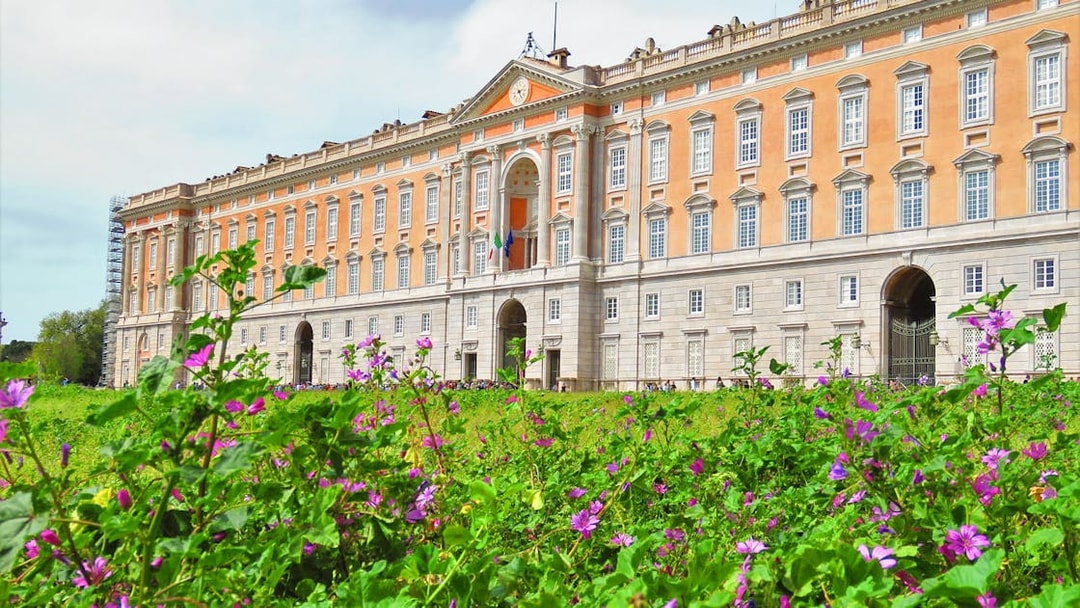Royal Palace of Caserta facade with blooming flowers in foreground, Caserta, Italy.