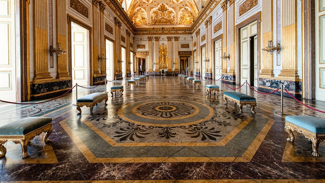 Royal Palace of Caserta grand hall with ornate ceiling and marble floor.