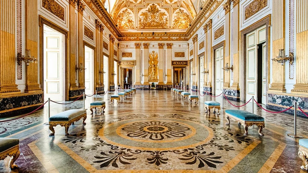 Ornate hall with gilded ceiling and marble floor inside Royal Palace of Caserta.