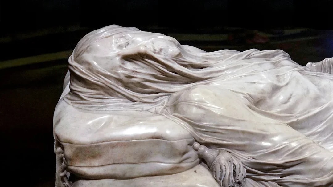 Close-up of the Veiled Christ statue in Naples, Italy, showcasing intricate marble drapery.