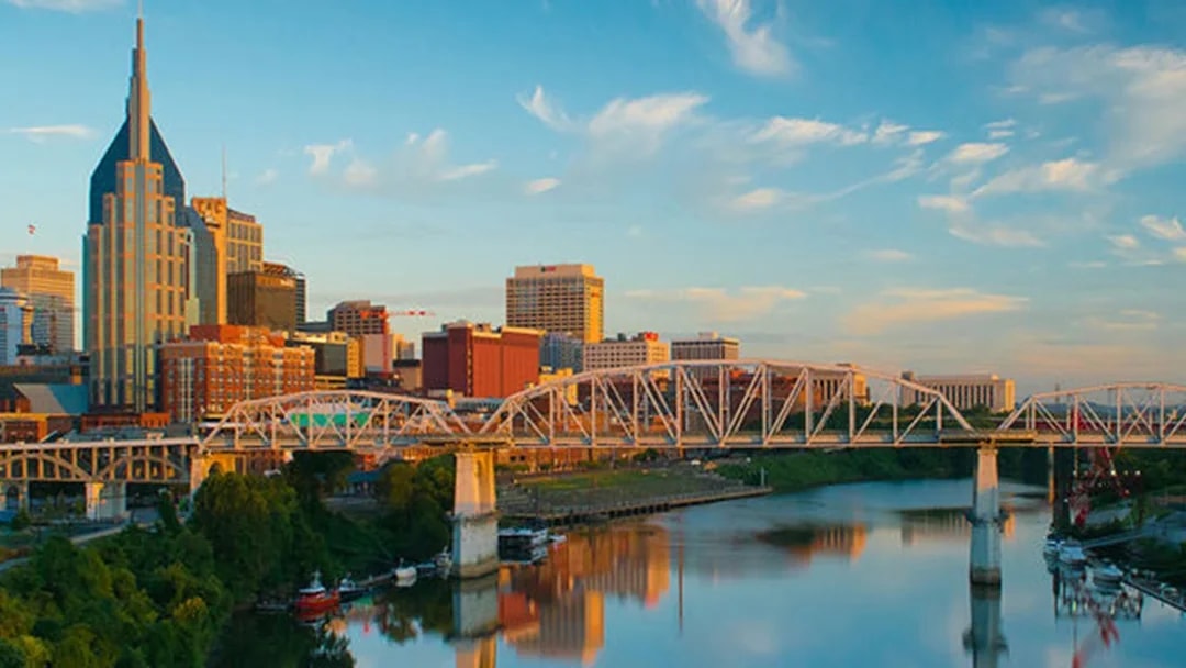 Nashville skyline with bridge over Cumberland River at sunset.
