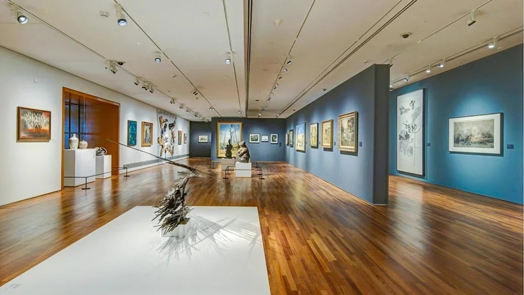 National Gallery Singapore interior with diverse art exhibits displayed on walls and sculptures on the floor.