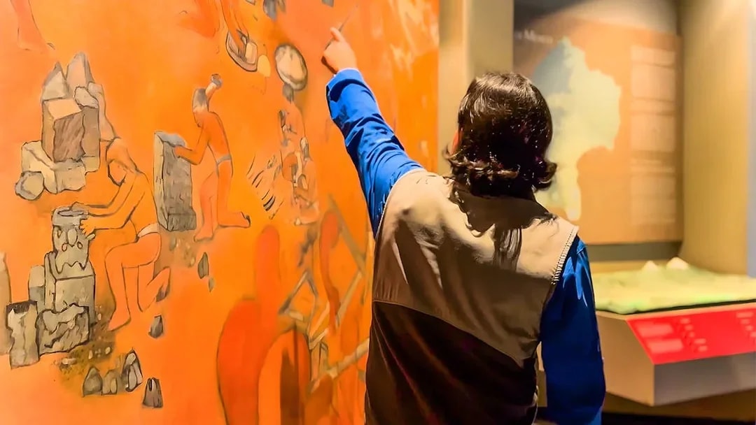 Visitor pointing at mural in the National Museum of Anthropology, Mexico City.