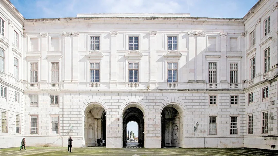 Courtyard of National Palace of Ajuda, Lisbon with arched entrance and visitors.