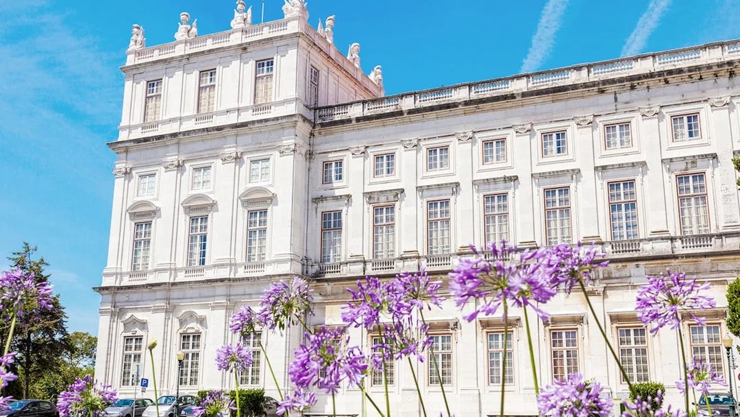 National Palace of Ajuda facade with purple flowers in Lisbon, Portugal.