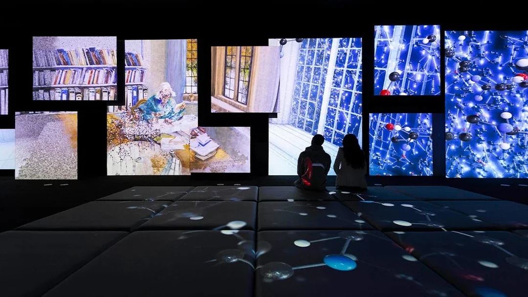 Frameless National Portrait Gallery exhibit with digital art projections and visitors seated.