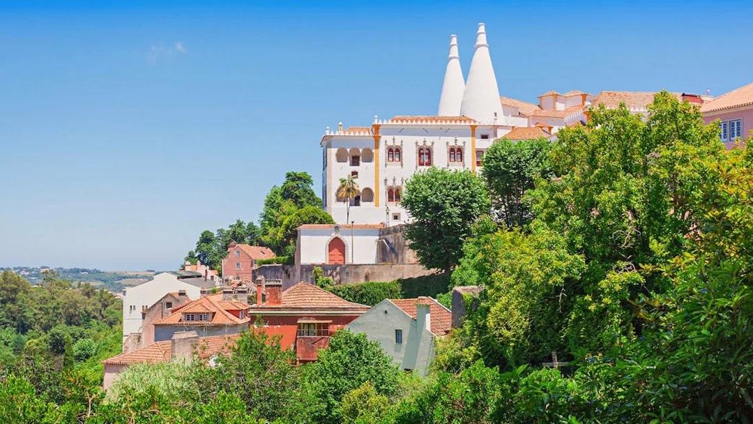 National Sintra Palace with iconic chimneys surrounded by lush greenery in Sintra, Portugal.