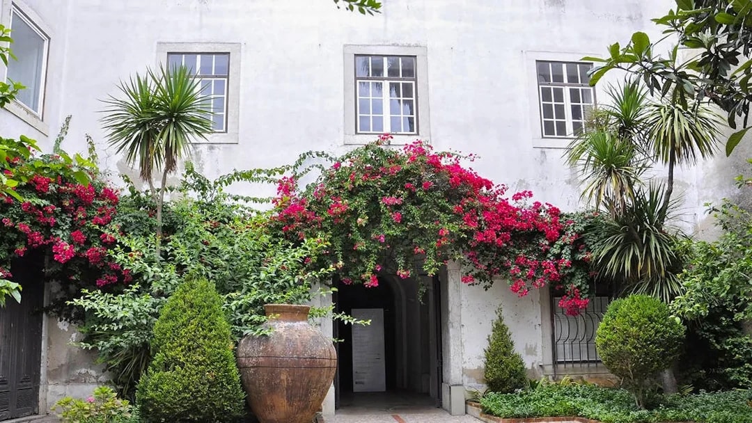 National Tile Museum courtyard with lush greenery and vibrant flowers, Lisbon.