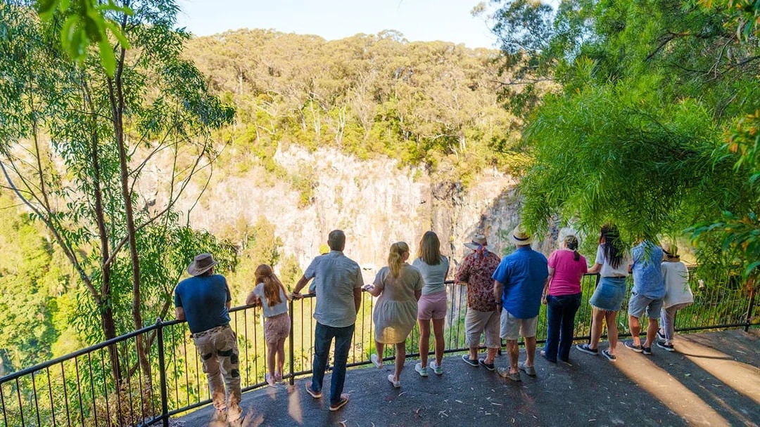 Tourists viewing Springbrook Waterfalls from a lookout on the Natural Bridge tour.