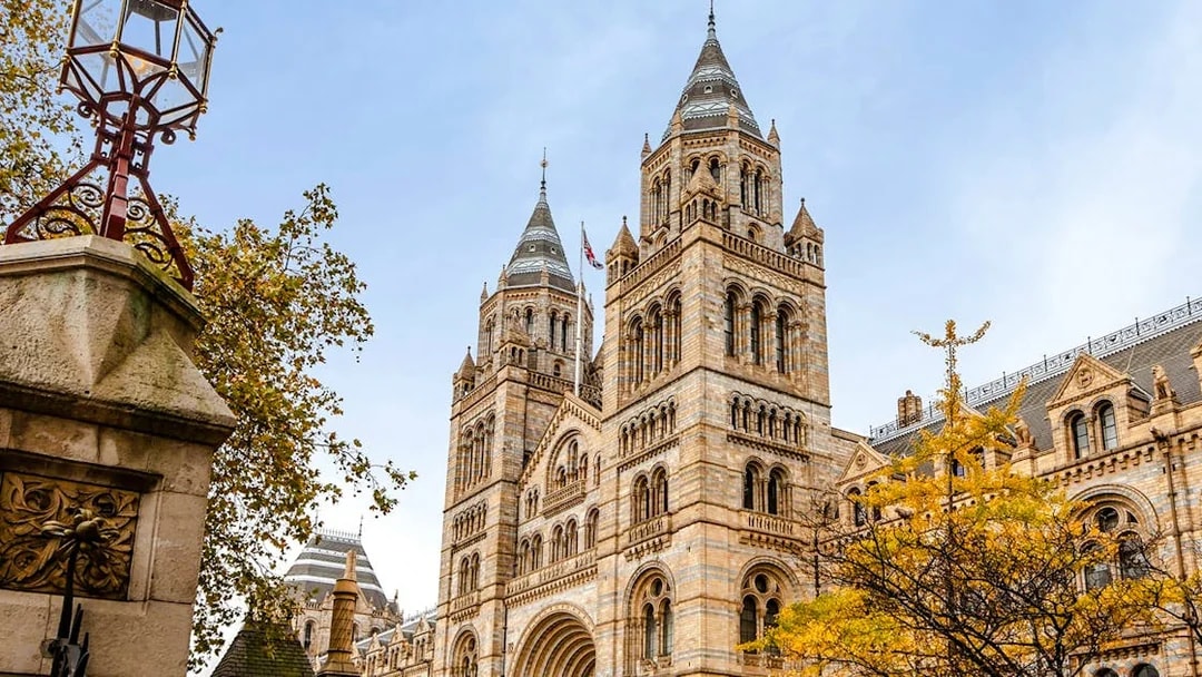 Natural History Museum exterior with twin towers and autumn trees in London.