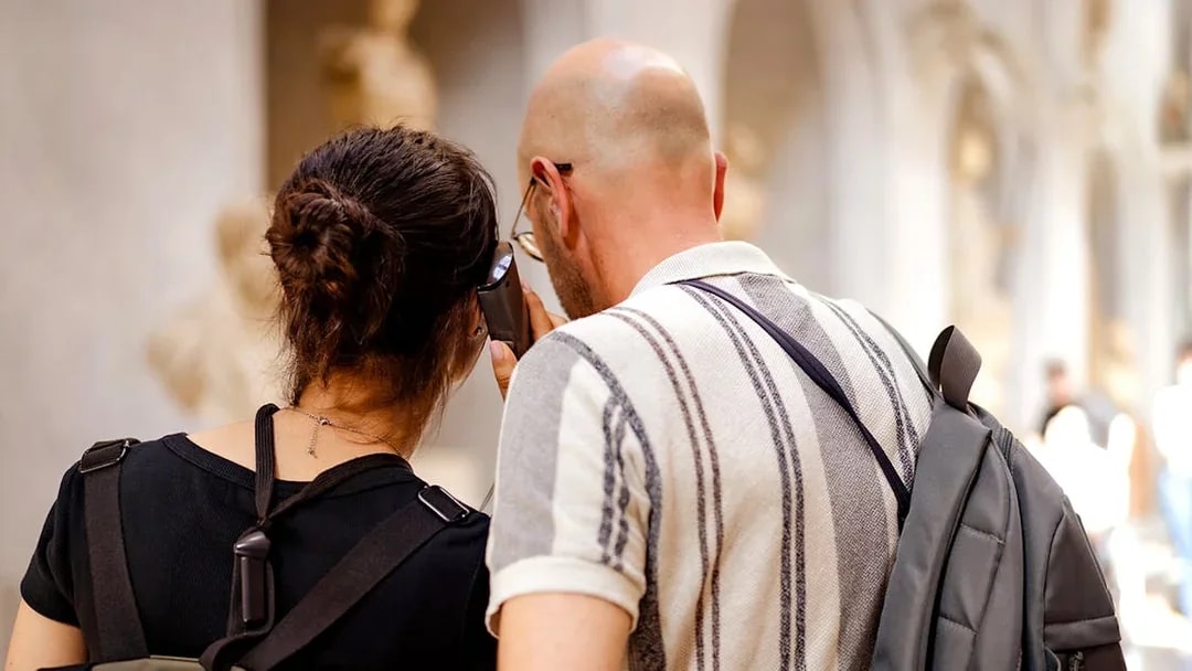 Guests using audio guide in museum hallway.