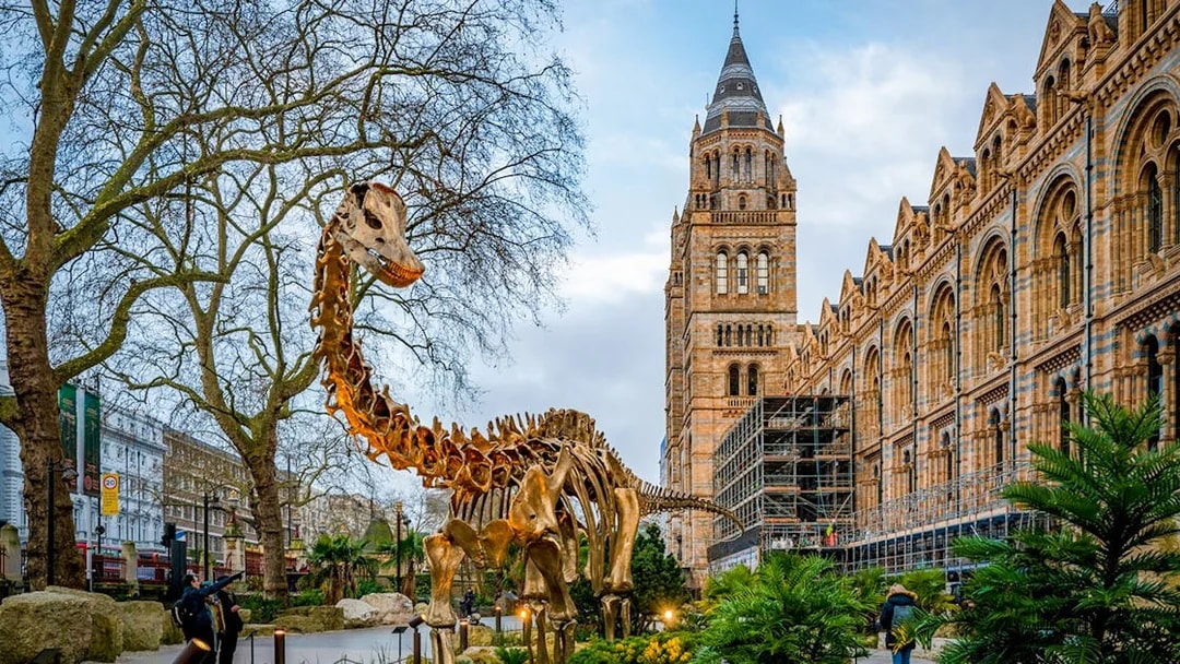 Dinosaur sculpture outside Natural History Museum, London, with historic architecture in the background.