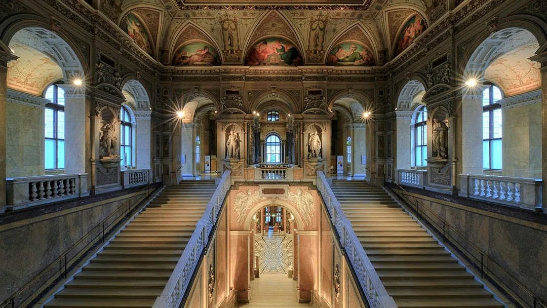 Staircase with ornate ceiling and statues inside Natural History Museum Vienna.