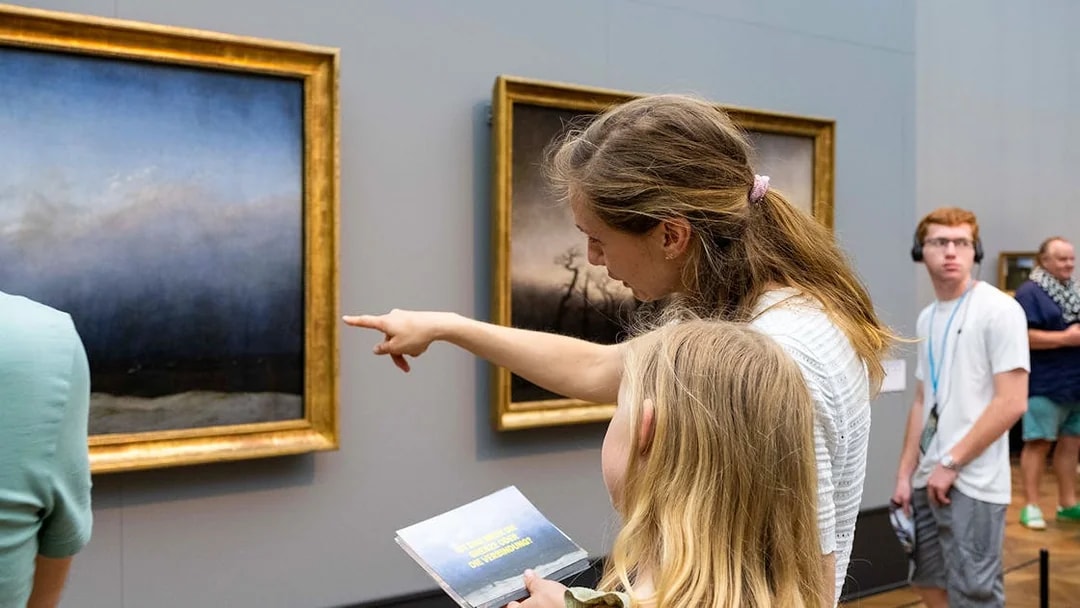 Visitors observing paintings at Neues Museum, Berlin.