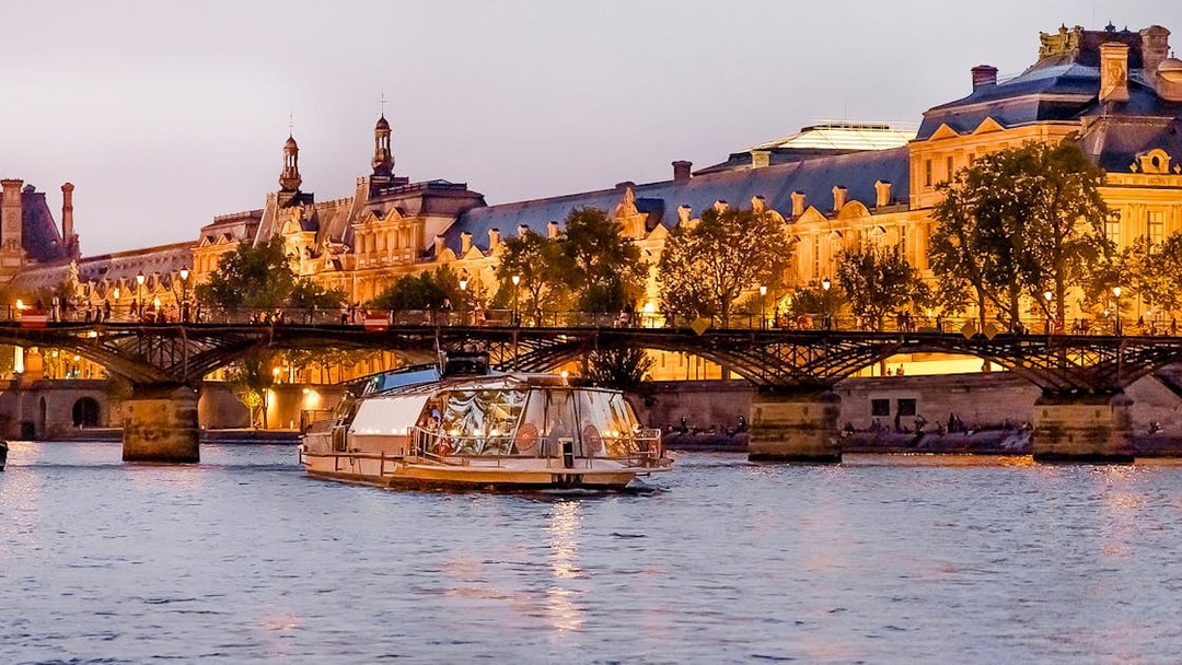 Bateaux Parisiens cruise on the Seine River with illuminated Parisian architecture in the background.