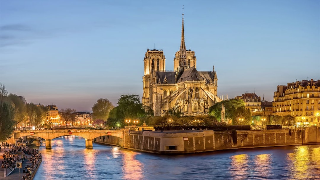 Notre-Dame de Paris illuminated at dusk during city tour along the Seine River.