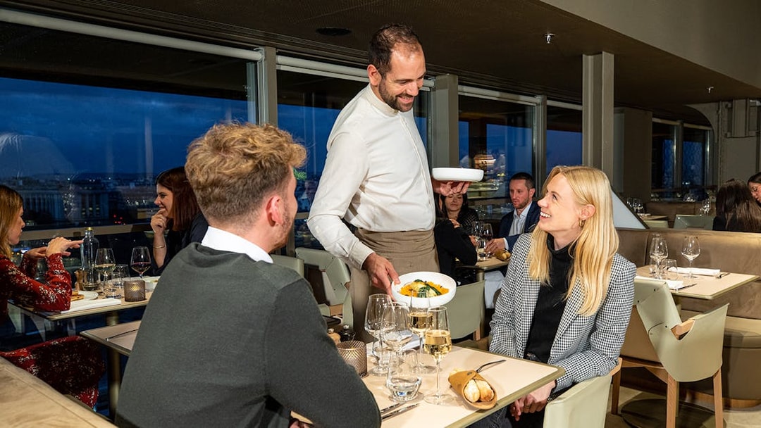 Server presenting dinner to a couple at Madame Brasserie, Eiffel Tower, Paris.