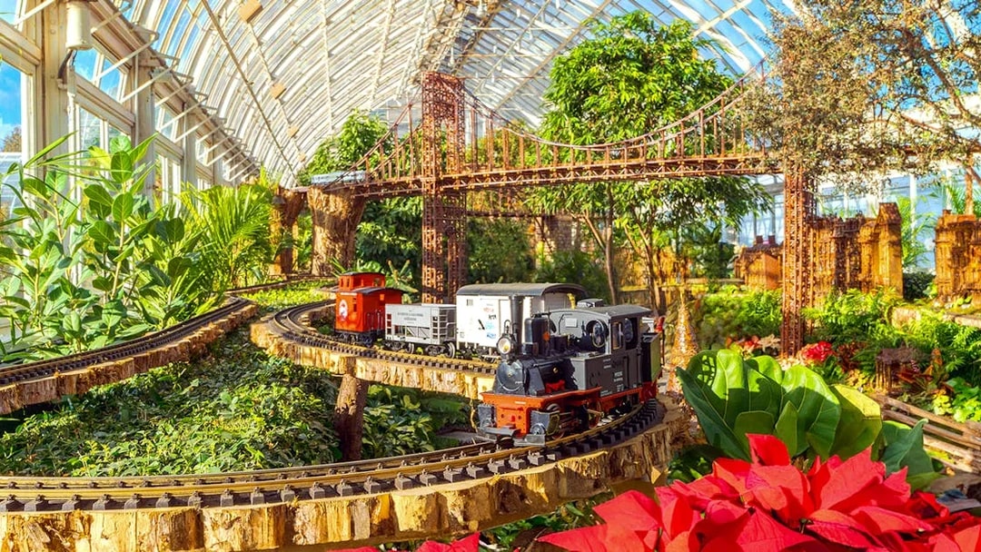 Model trains on tracks with festive decorations at New York Botanical Gardens.