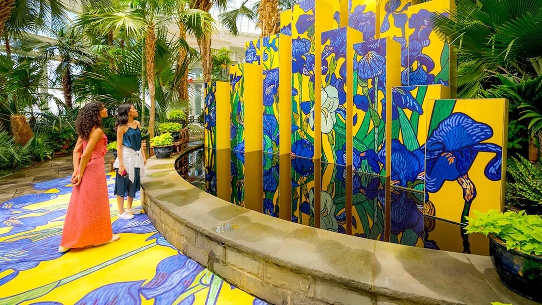 Guests viewing vibrant floral art installation at New York Botanical Garden.