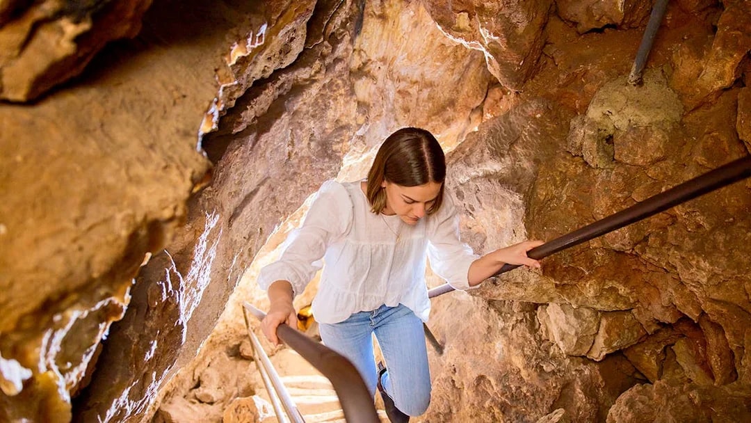 Visitor exploring Ngilgi Cave's rocky staircase during the Ancient Lands Experience.