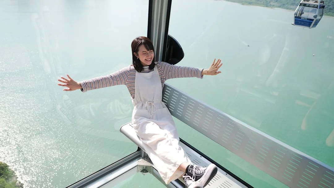 Person enjoying a ride in the Ngong Ping Cable Car over water in Hong Kong.