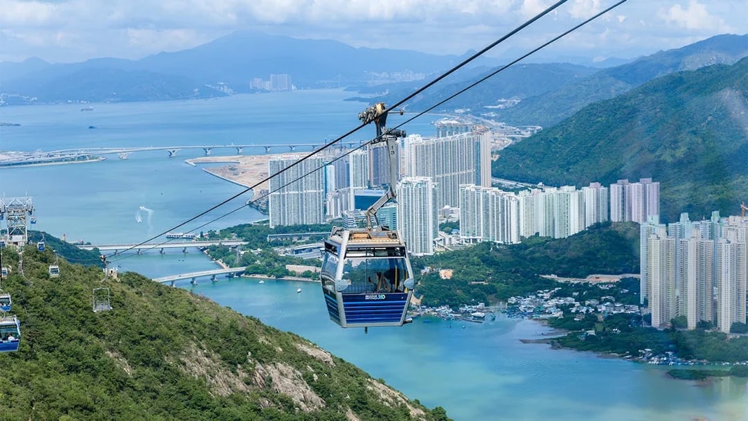 Cable car over Hong Kong landscape with city and water views.