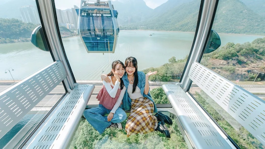 People enjoying a ride in a standard cable car at Ngong Ping, overlooking lush landscapes.