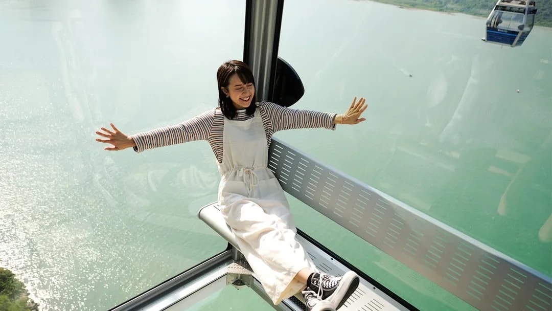 Person enjoying Ngong Ping Cable Car ride with scenic ocean view.
