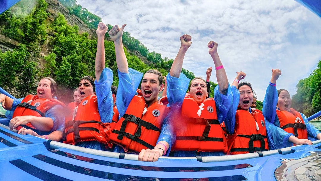 Guests enjoying Whirlpool Jet Boat Tour in Niagara Gorge, Canada, wearing life jackets and cheering.
