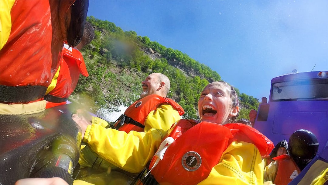 Guests enjoying Whirlpool Jet Boat Tour in Niagara Gorge, Canada, wearing life jackets.