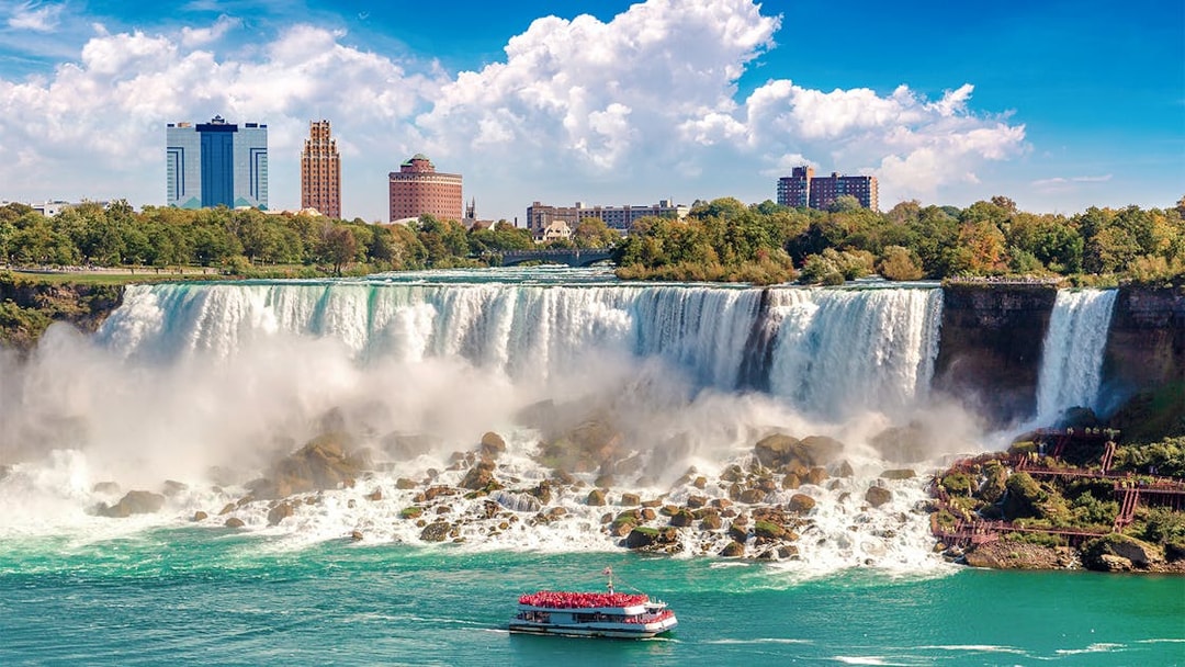 Hornblower Cruise boat approaching Niagara Falls, Canada with city skyline in the background.