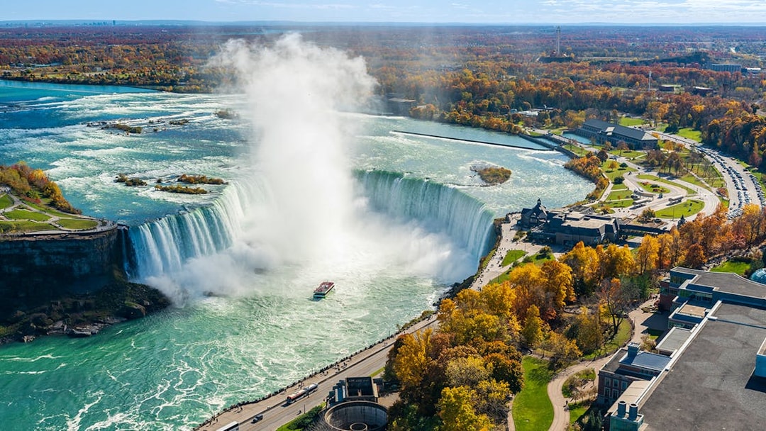 Niagara Falls view from Canada side with boat in misty water flow.