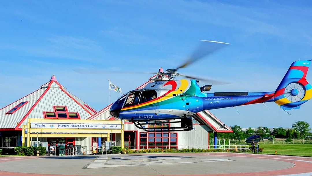 Helicopter taking off from Niagara Falls helipad for aerial tour.
