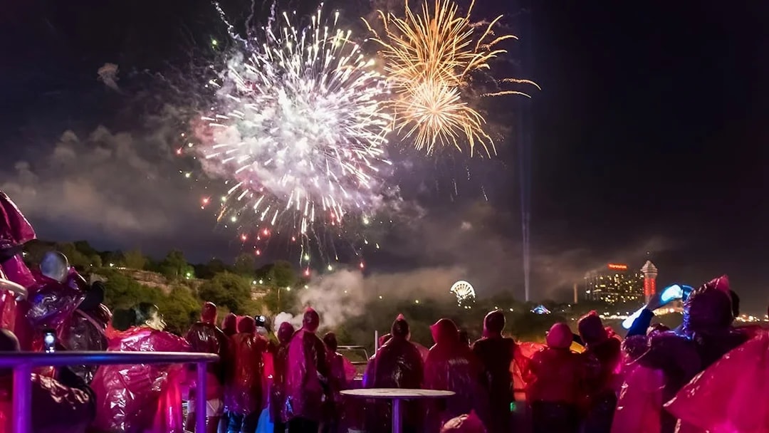 Small group watching fireworks display at night, Niagara Falls in the background.