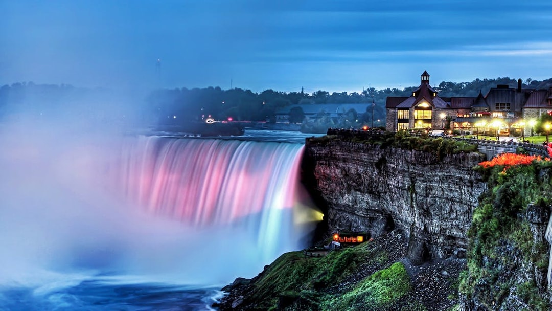 Niagara Falls illuminated at night with nearby buildings, part of Night on Niagara Walking Tour.