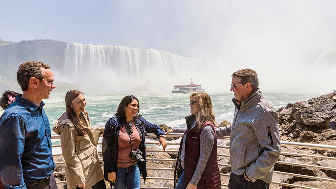 Tourists gathered at Niagara Falls with a boat in the background.