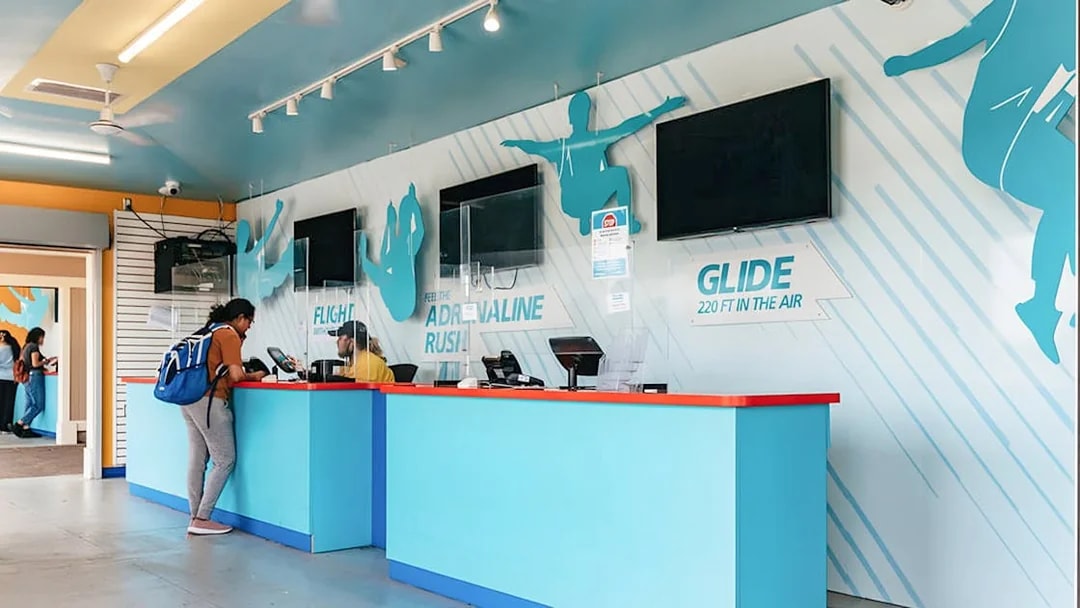 Zipline To The Falls ticket counter with customer and staff interaction.