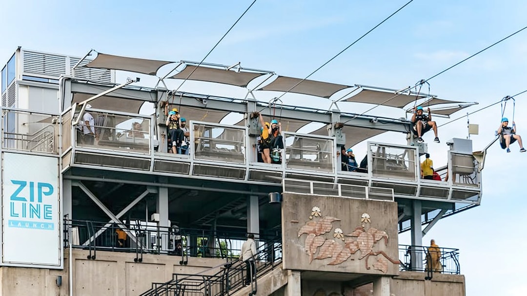 Zipline launch platform with people ziplining towards the falls.