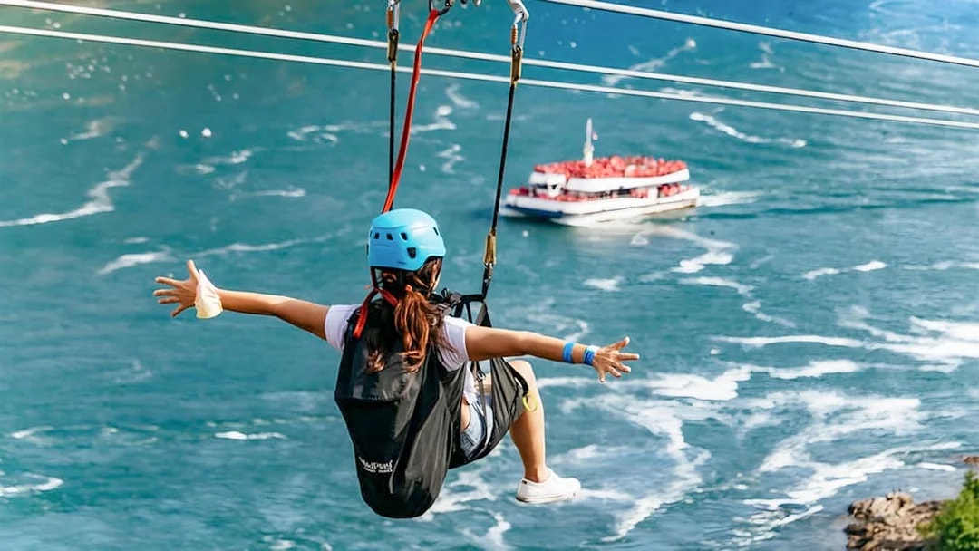 Person ziplining over water with a boat below at Niagara Falls.