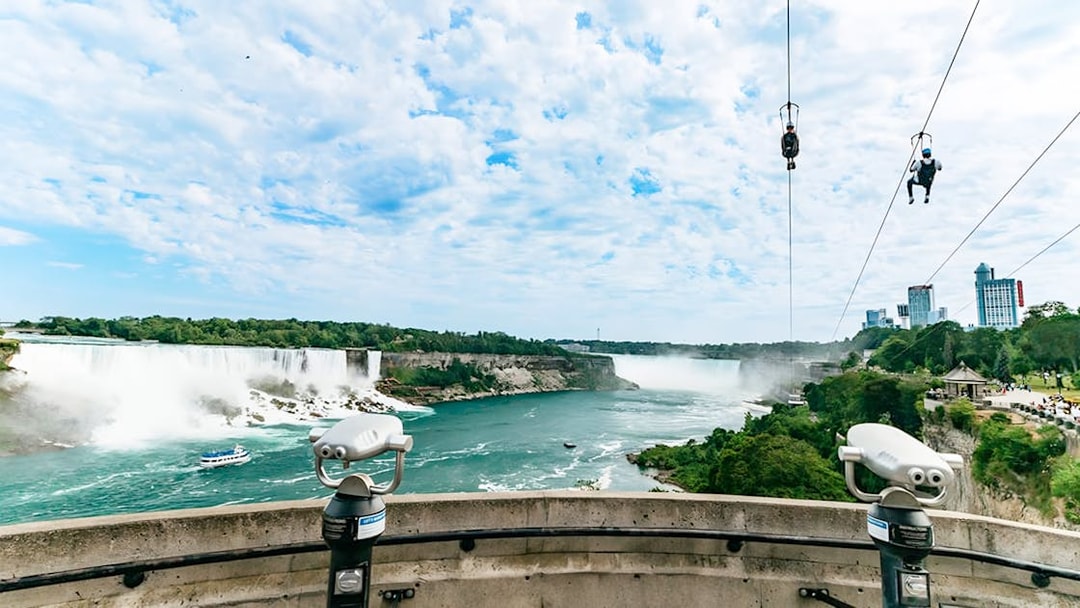Ziplining over Niagara Falls with city skyline and waterfalls in view.