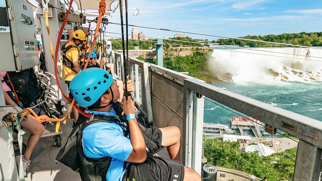 Visitors ziplining towards Niagara Falls with a view of the waterfall and surrounding landscape.