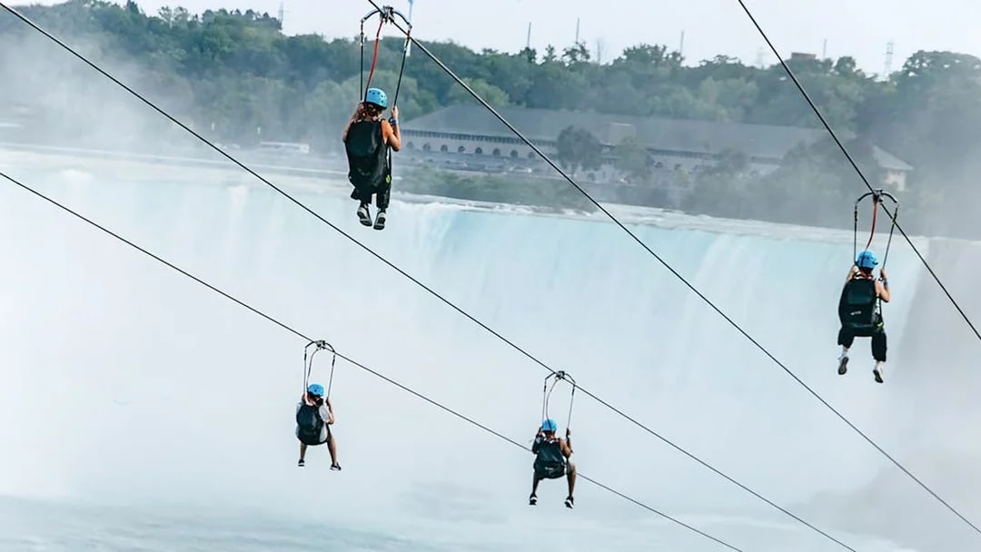 People ziplining towards Niagara Falls.