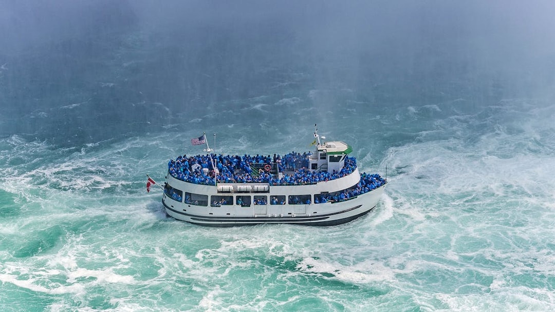 Tour boat near Niagara Falls with passengers in blue ponchos, USA.