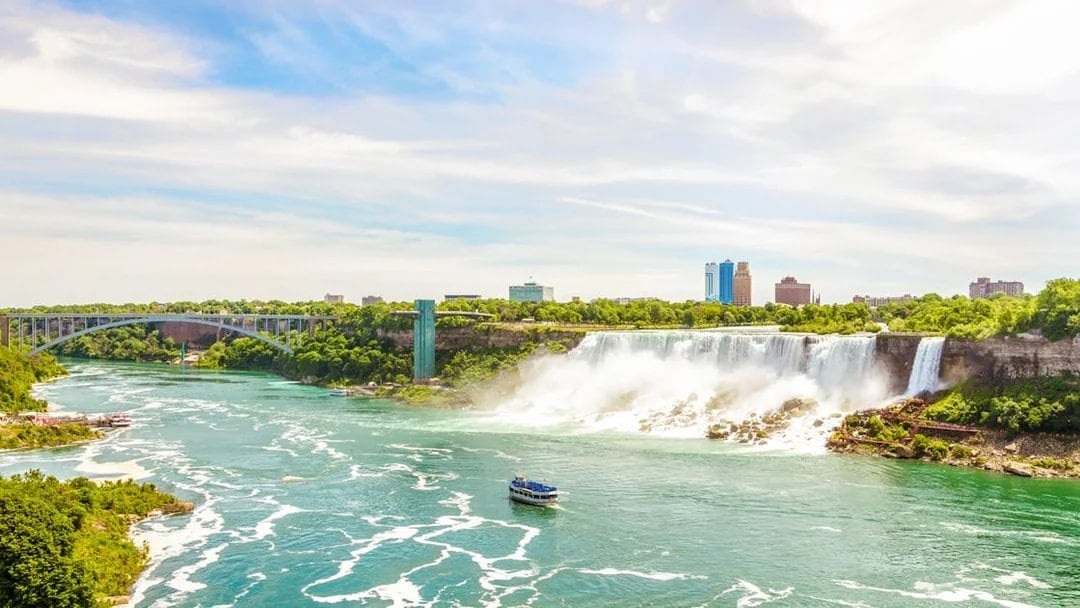 Rainbow International Bridge over Niagara River with boat and falls in view.