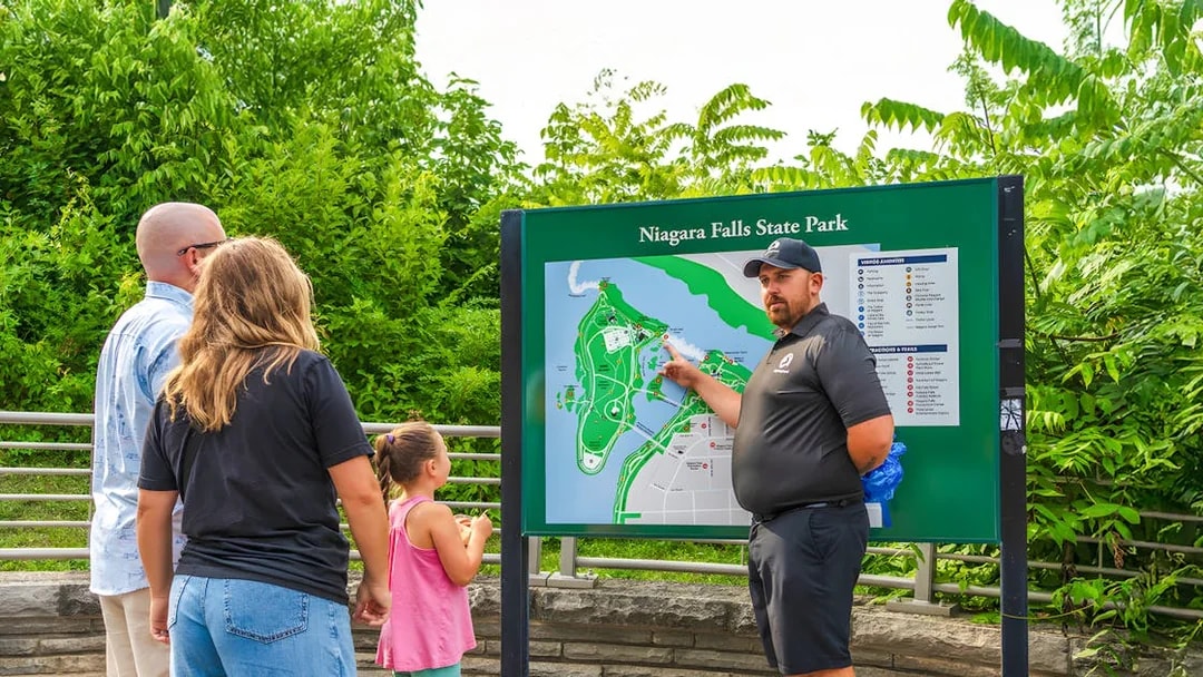 Family learning about Niagara Falls at a park map with a guide.