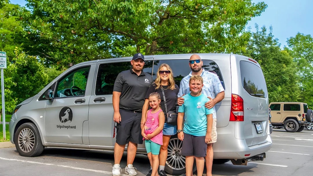Family posing with tour van at Niagara Falls parking area.